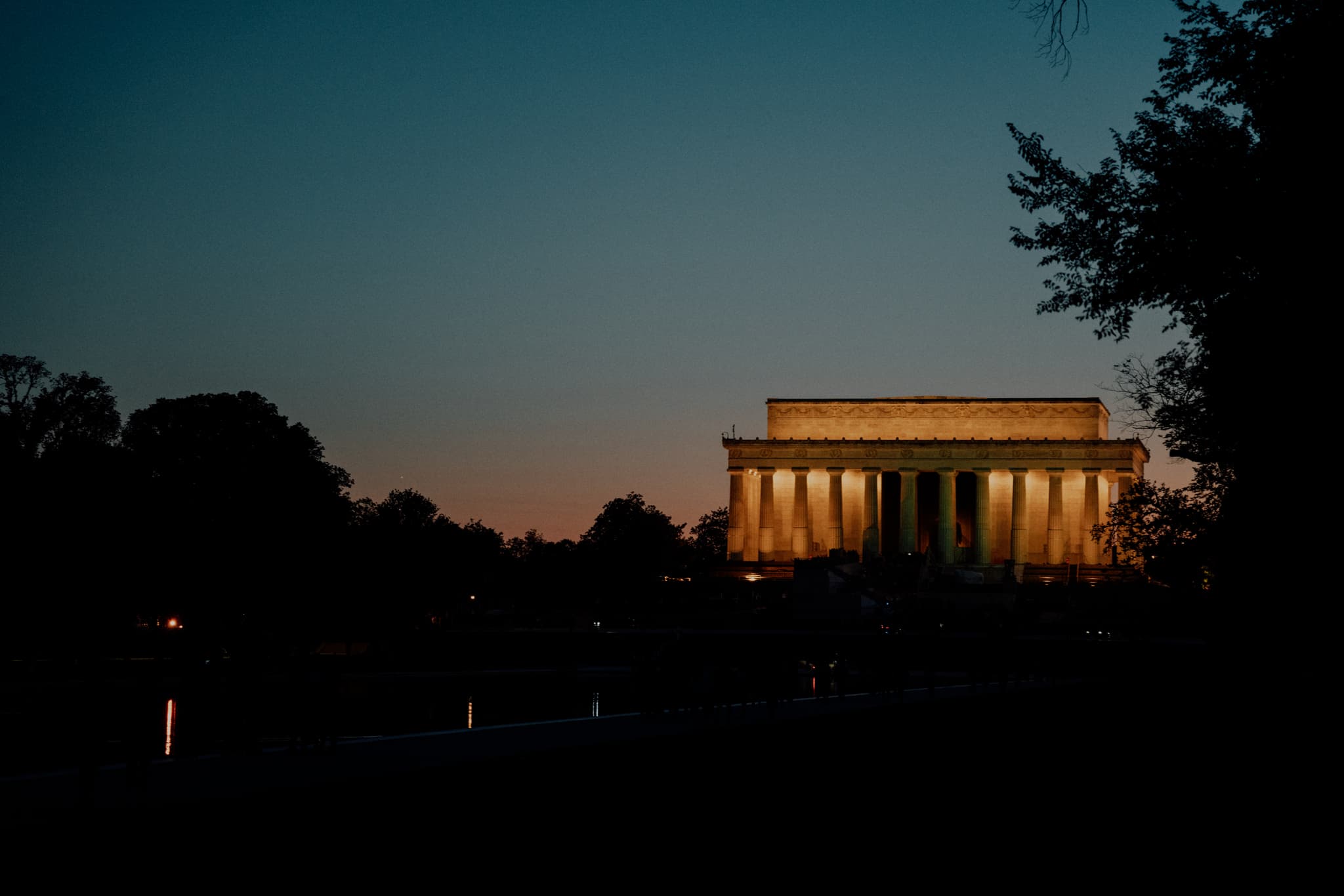 A twilight view of the Lincoln Memorial with a silhouette of trees against a dusky sky