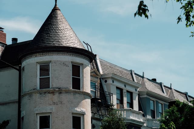 A row of houses with a prominent turret on a sunny day, featuring clear skies and lush greenery