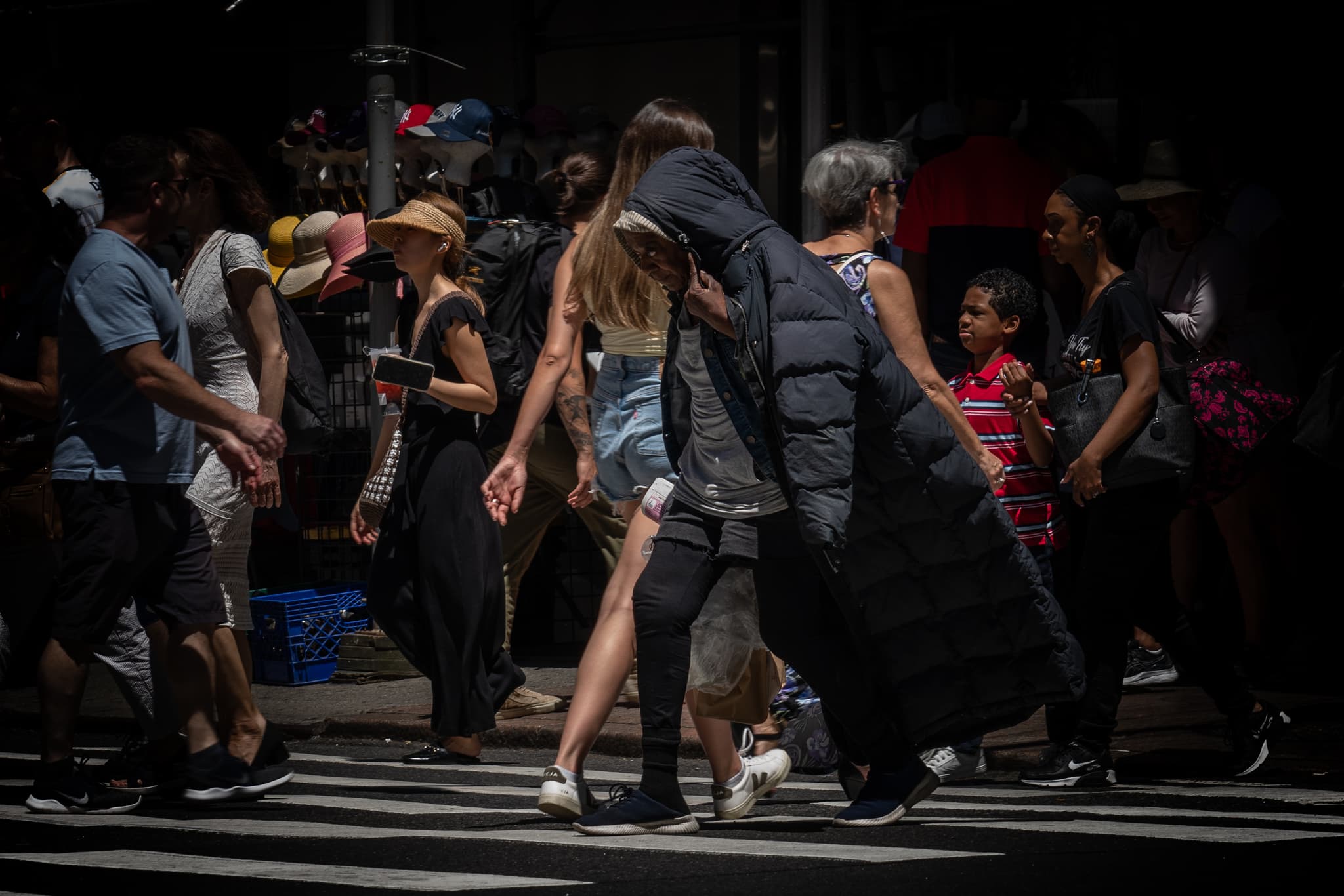 A group of people crossing a street, with a spotlight effect highlighting two individuals in the center while the surroundings are dimmed