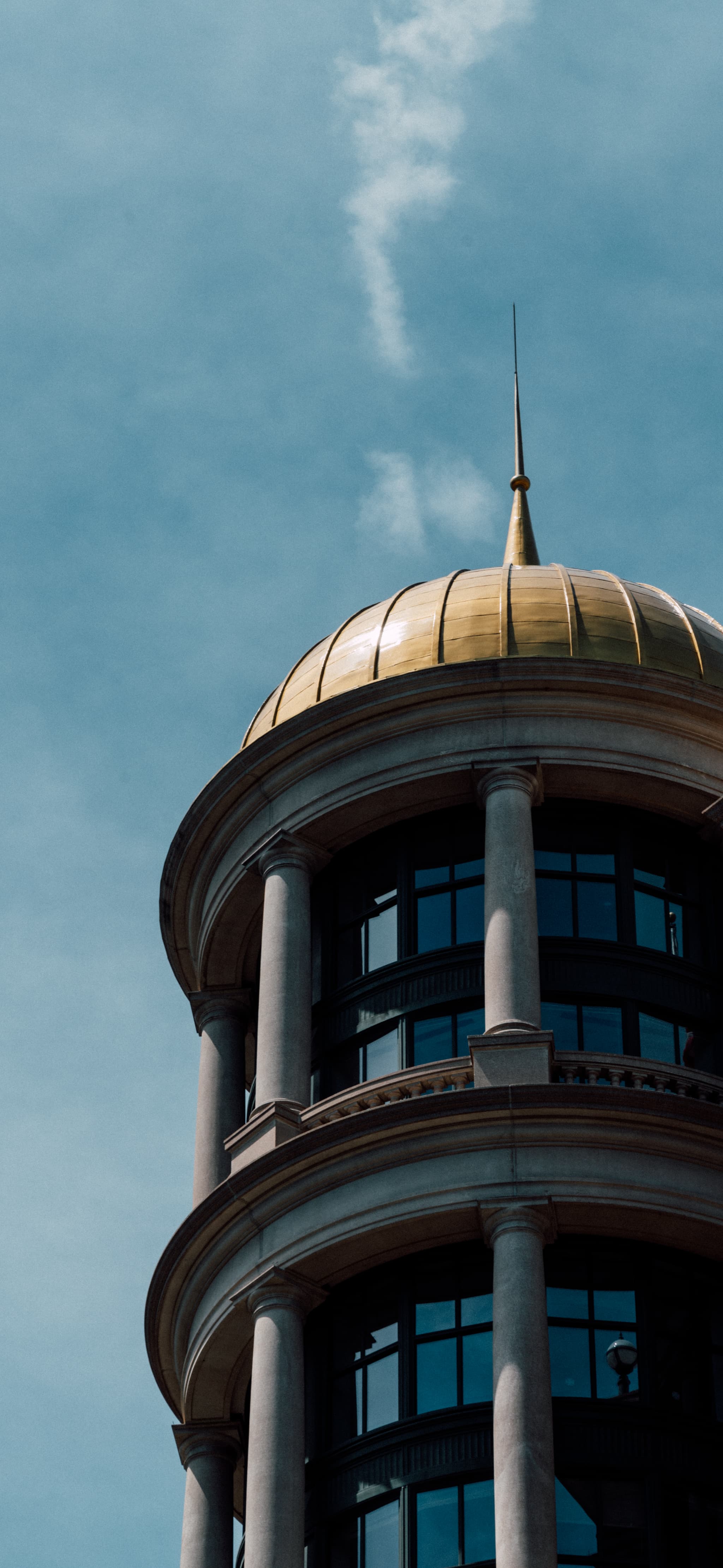 A golden-domed tower against a blue sky with wispy clouds