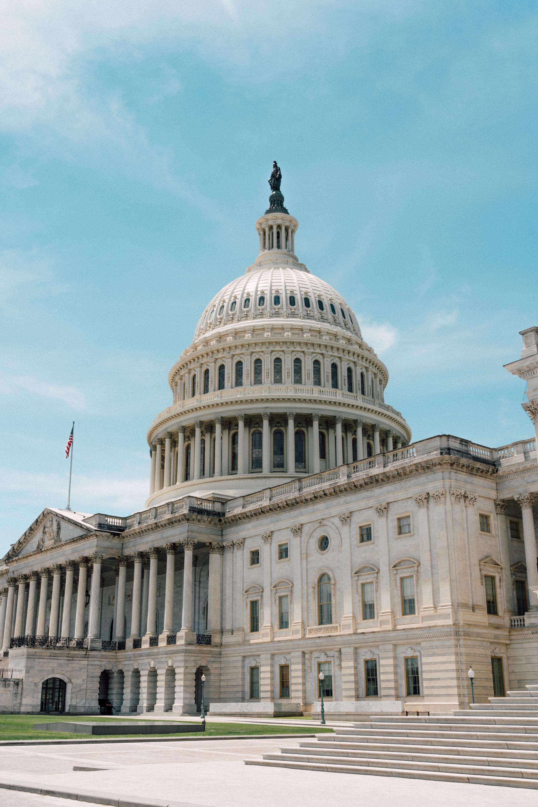 The United States Capitol building under a clear blue sky, featuring its iconic dome and neoclassical architecture