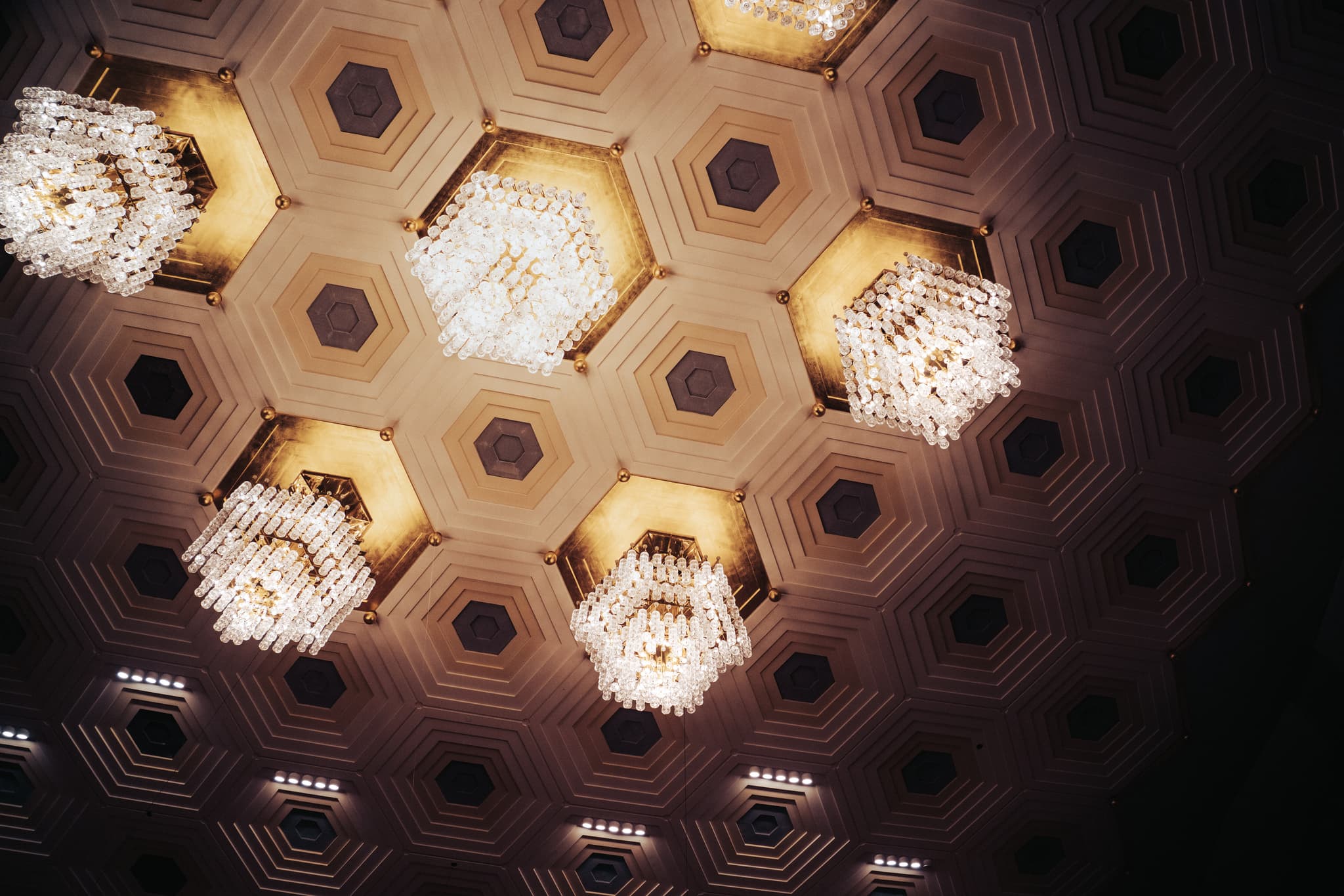 A patterned ceiling with hexagonal shapes and recessed lighting fixtures