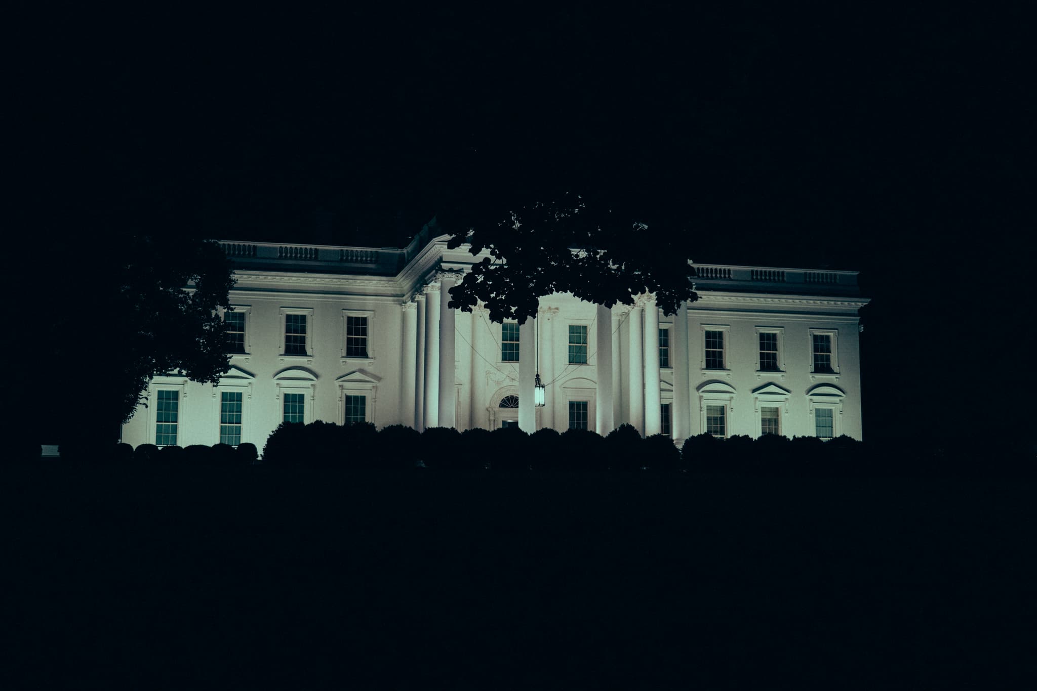 A nighttime view of the White House illuminated against a dark sky