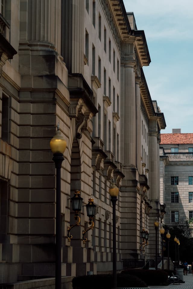 A row of ornate street lamps in front of a classical building with columns and detailed stonework