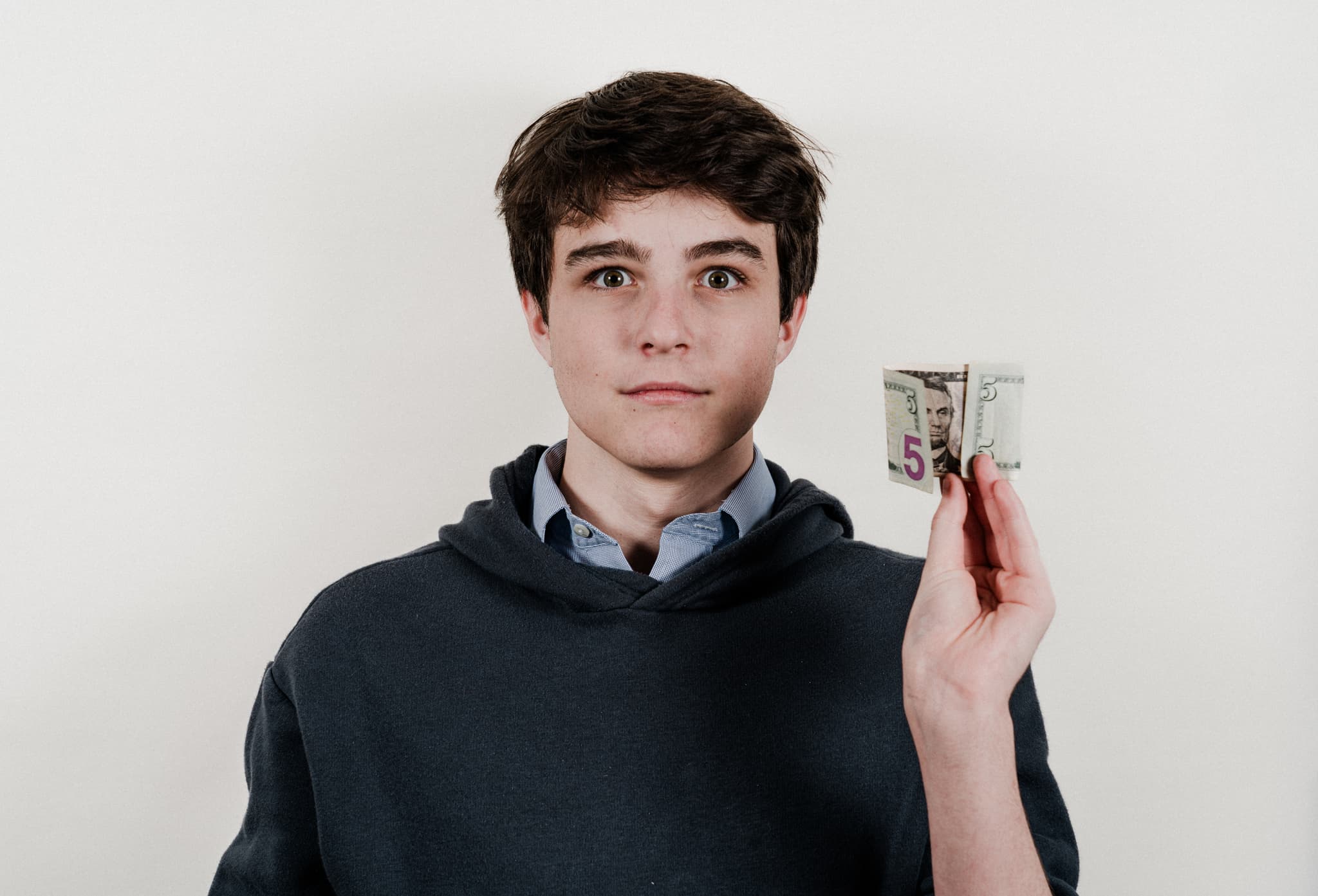 A young man with a surprised expression holding a small stack of money