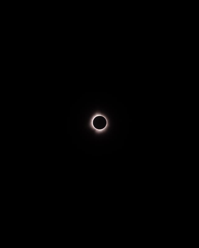 A solar eclipse with the moon blocking the sun, creating a bright corona visible against a dark sky