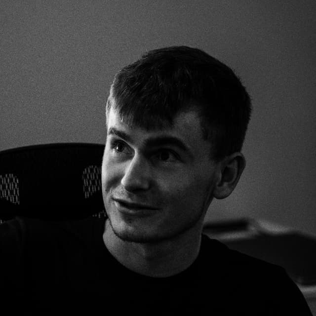 A black and white portrait of a smiling young man looking to the side